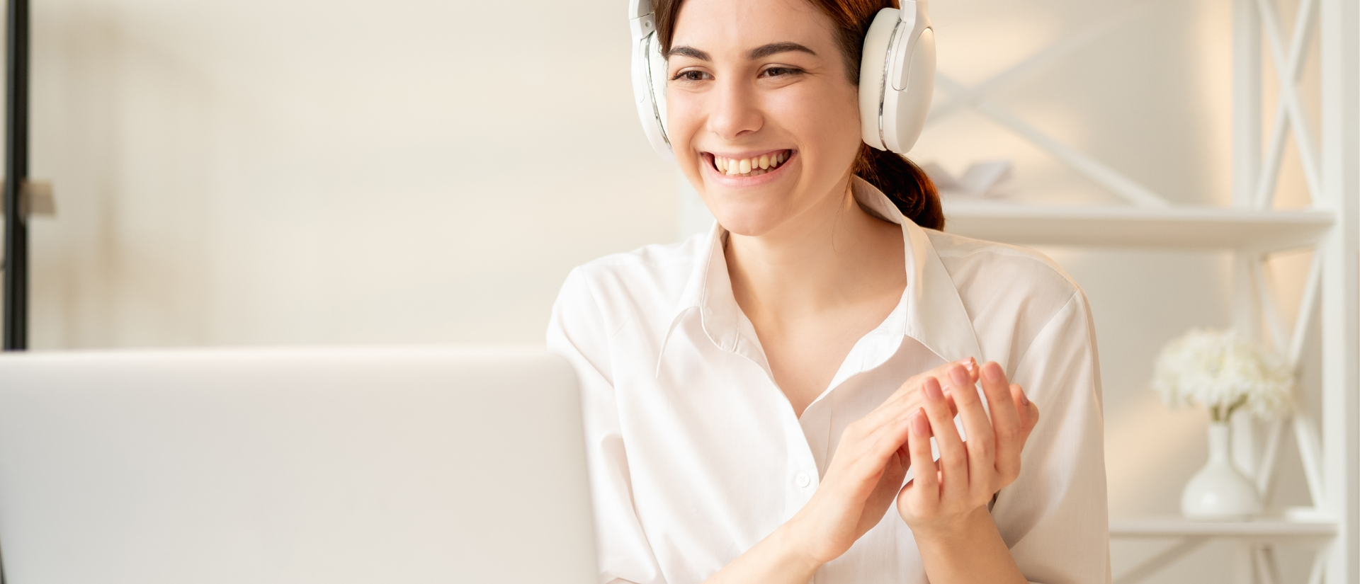 A woman looks at a computer with headphones on
